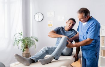 Orthopedic doctor consulting an Afro-American man with knee joint pain.