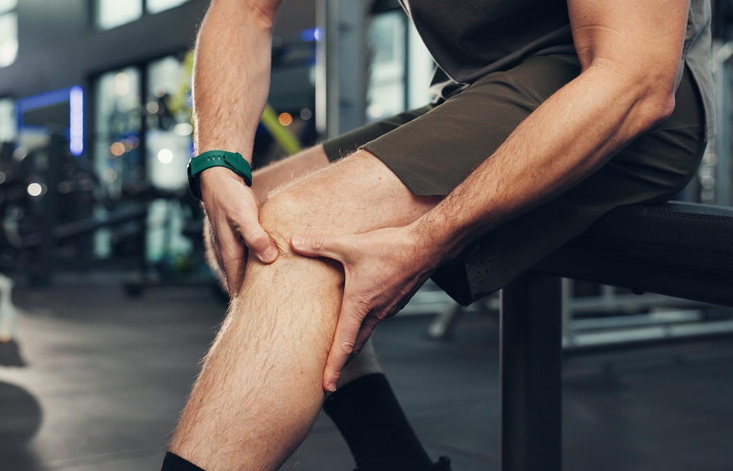 Exercise, knee pain and hands of person in gym for physical training or workout accident. Fitness, injury and legs with hurt athlete in health club for emergency, joint inflammation or strain.